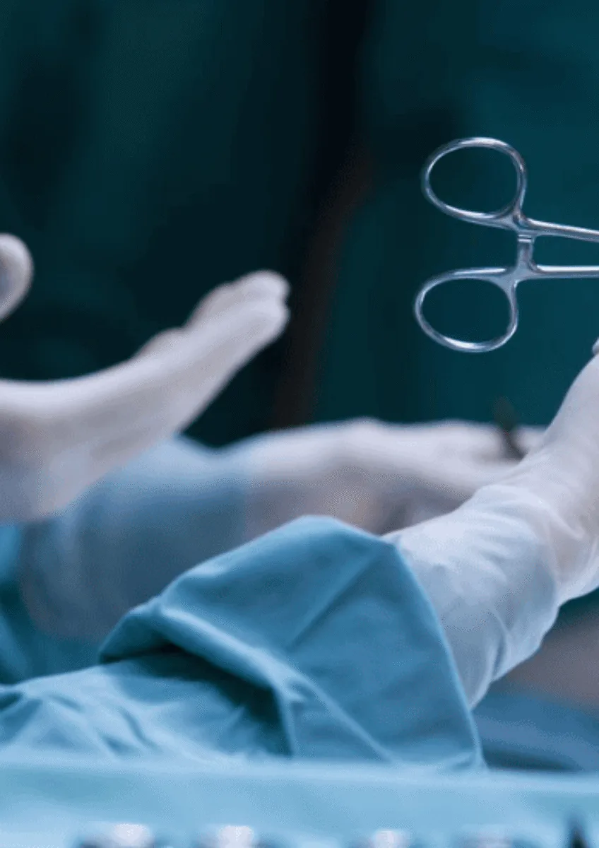 Gloved medical staff hands passing surgical scissors in operating theatre