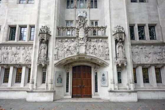 Ornate stone façade of Supreme Court building with large wooden doors