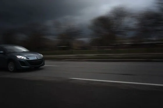 Dark car driving quickly on a road with blurred motion effect