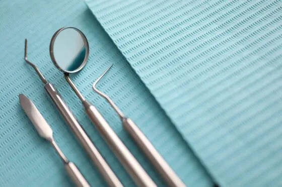 Four stainless steel dental examination tools on a blue dental bib