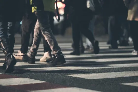 Various people crossing a zebra crossing at night