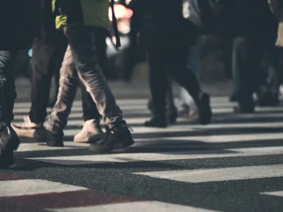 Various people crossing a zebra crossing at night