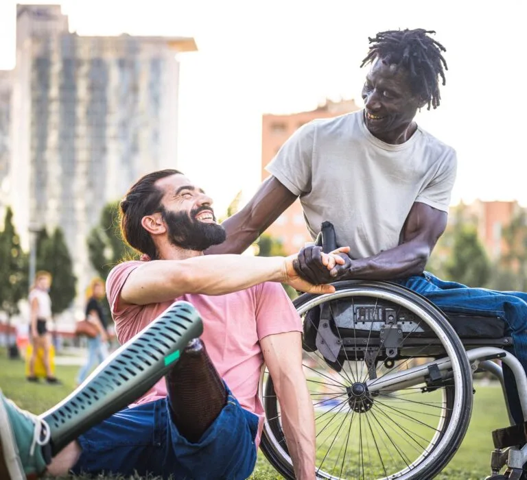 Two friends who have different physical disabilities greet each