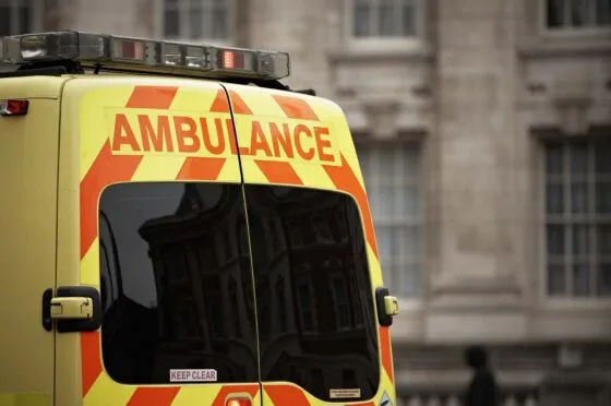 Rear of a yellow ambulance with orange chevrons and 'AMBULANCE' text