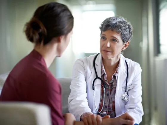 Doctor with stethoscope talking to woman in a consultation room