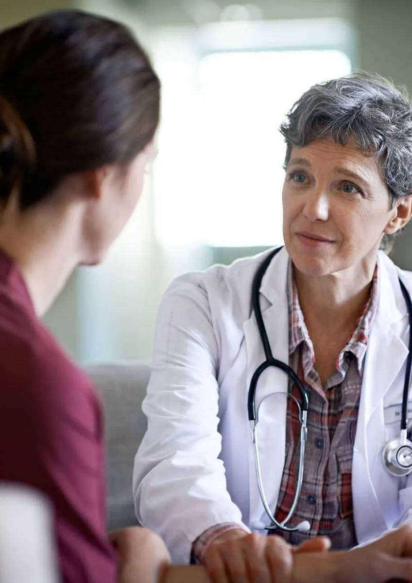 Doctor with stethoscope talking to woman in a consultation room