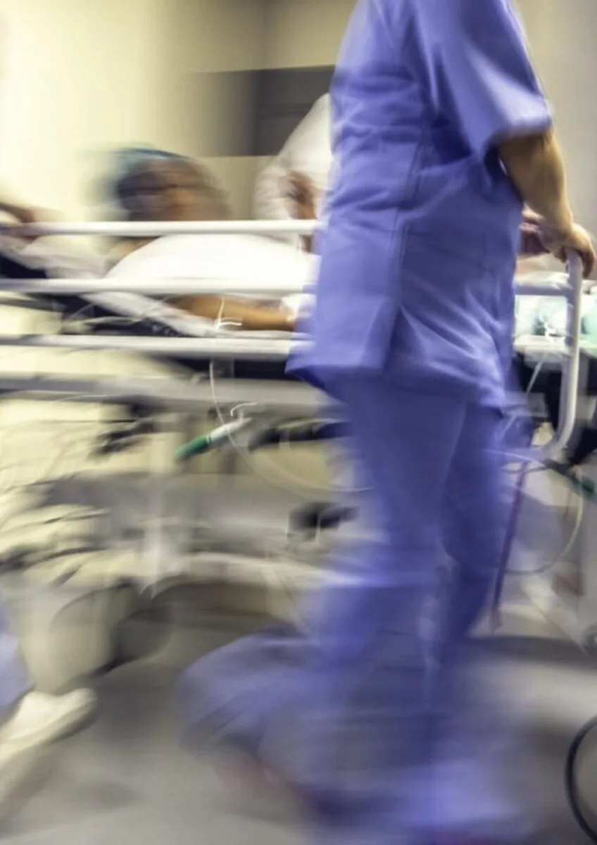 Blurred hospital corridor with medical staff pushing patient on trolley