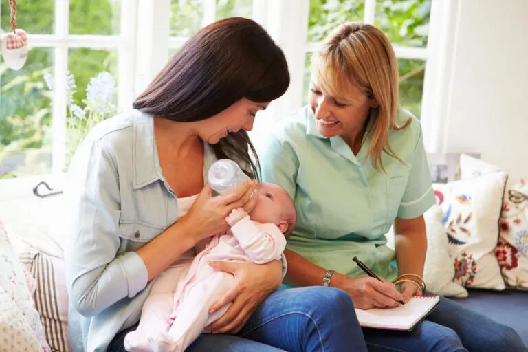 Mother feeding baby with-midwife
