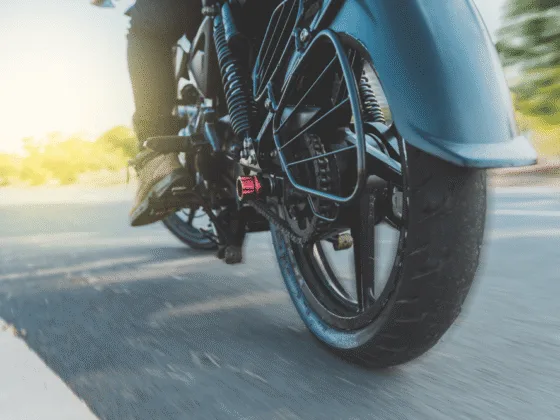 Close-up of motorcycle rear wheel and chain with rider on road