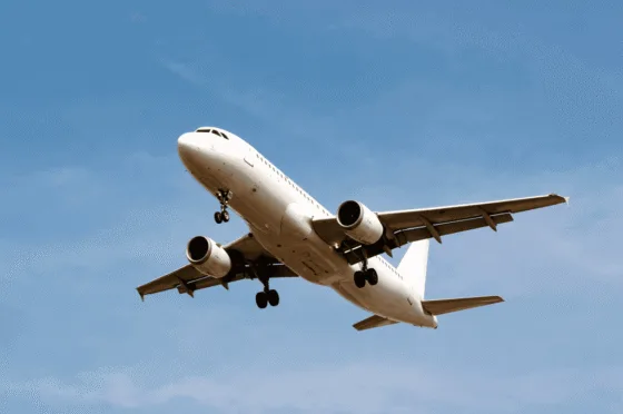 White commercial airplane descending with landing gear down against blue sky