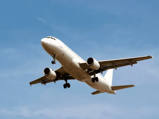 White passenger airplane landing with landing gear down in blue sky