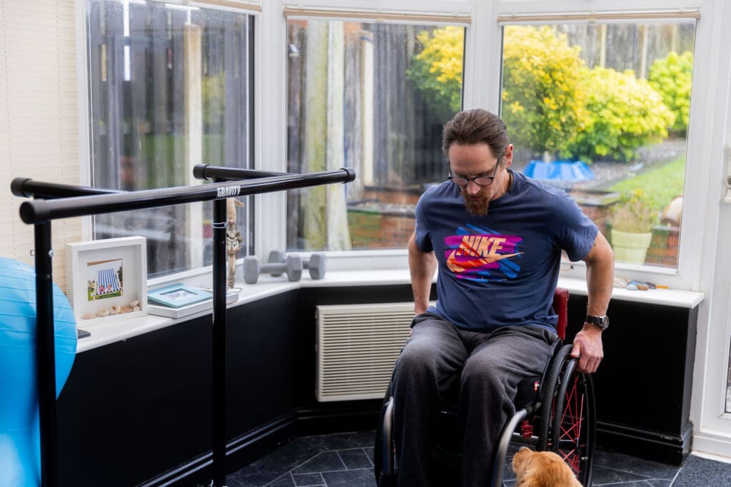 Ian using parallel bars during wheelchair rehabilitation