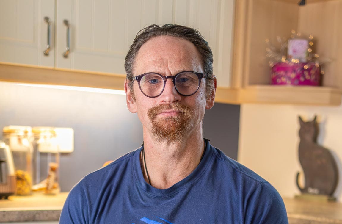 Ian Westmoreland with glasses seated in kitchen