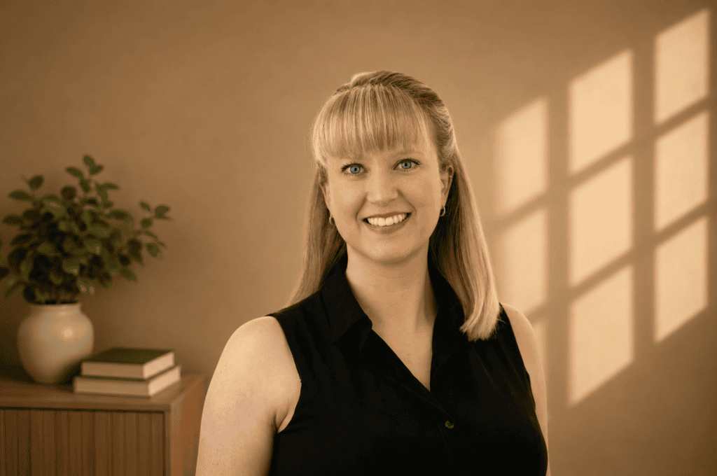 Blonde woman in black sleeveless top smiling in softly lit room