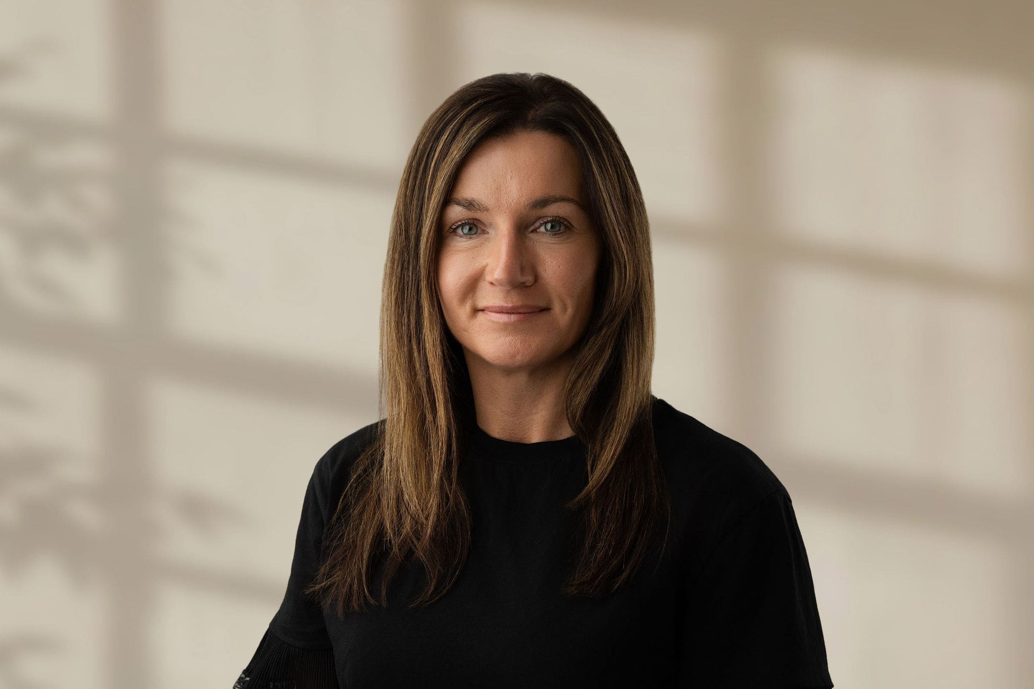 Lena Farnell looking at camera wearing a black top with straight light brown hair and a neutral expression