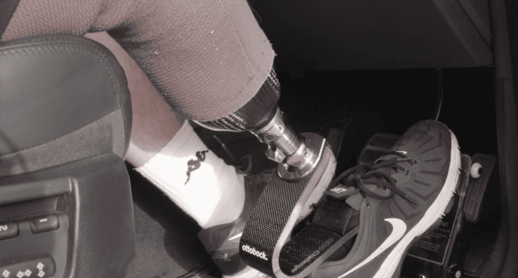 Close-up of a prosthetic leg pressing car pedals on the driver's side