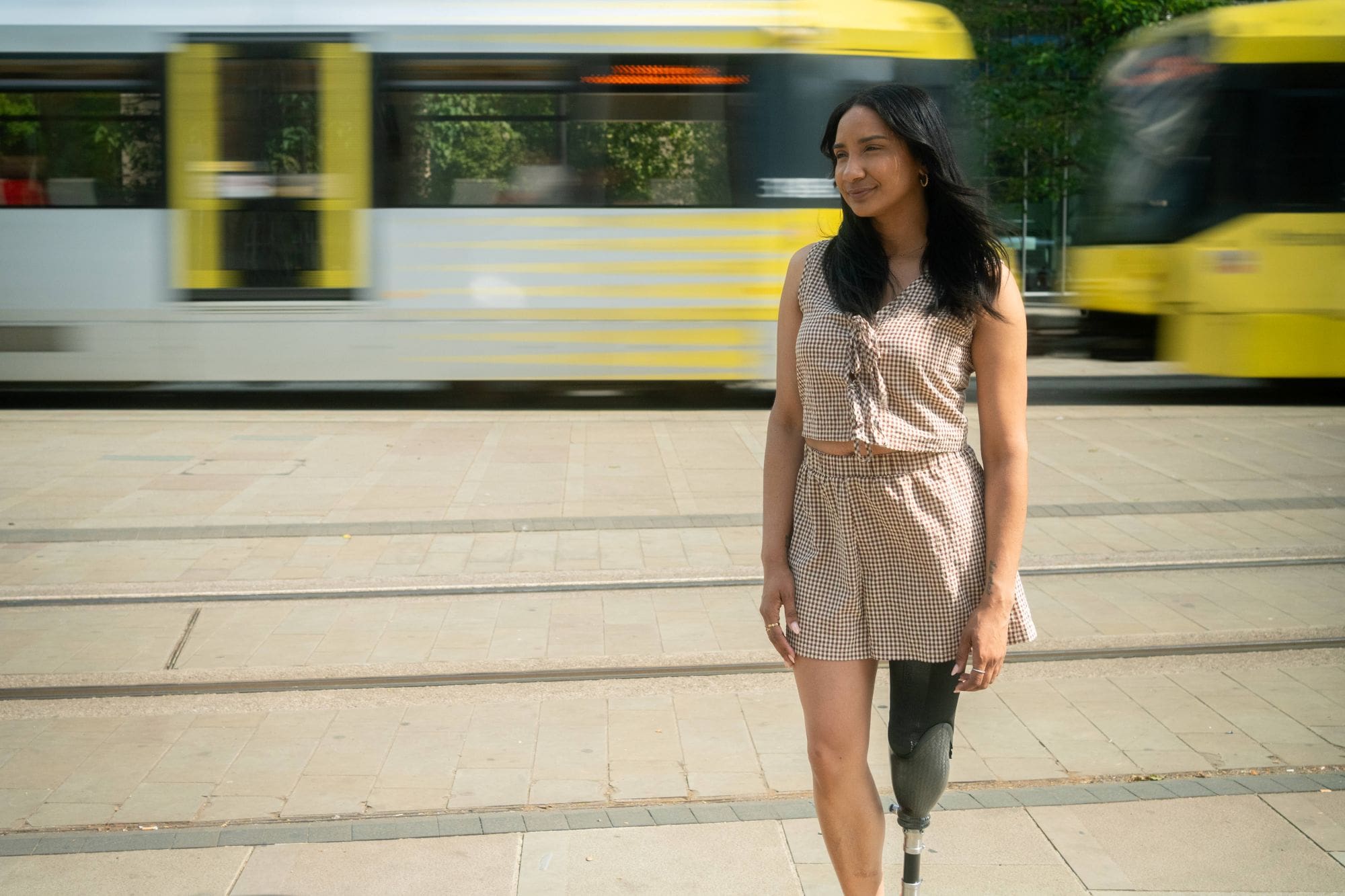 Woman with prosthetic leg standing near tram in urban area