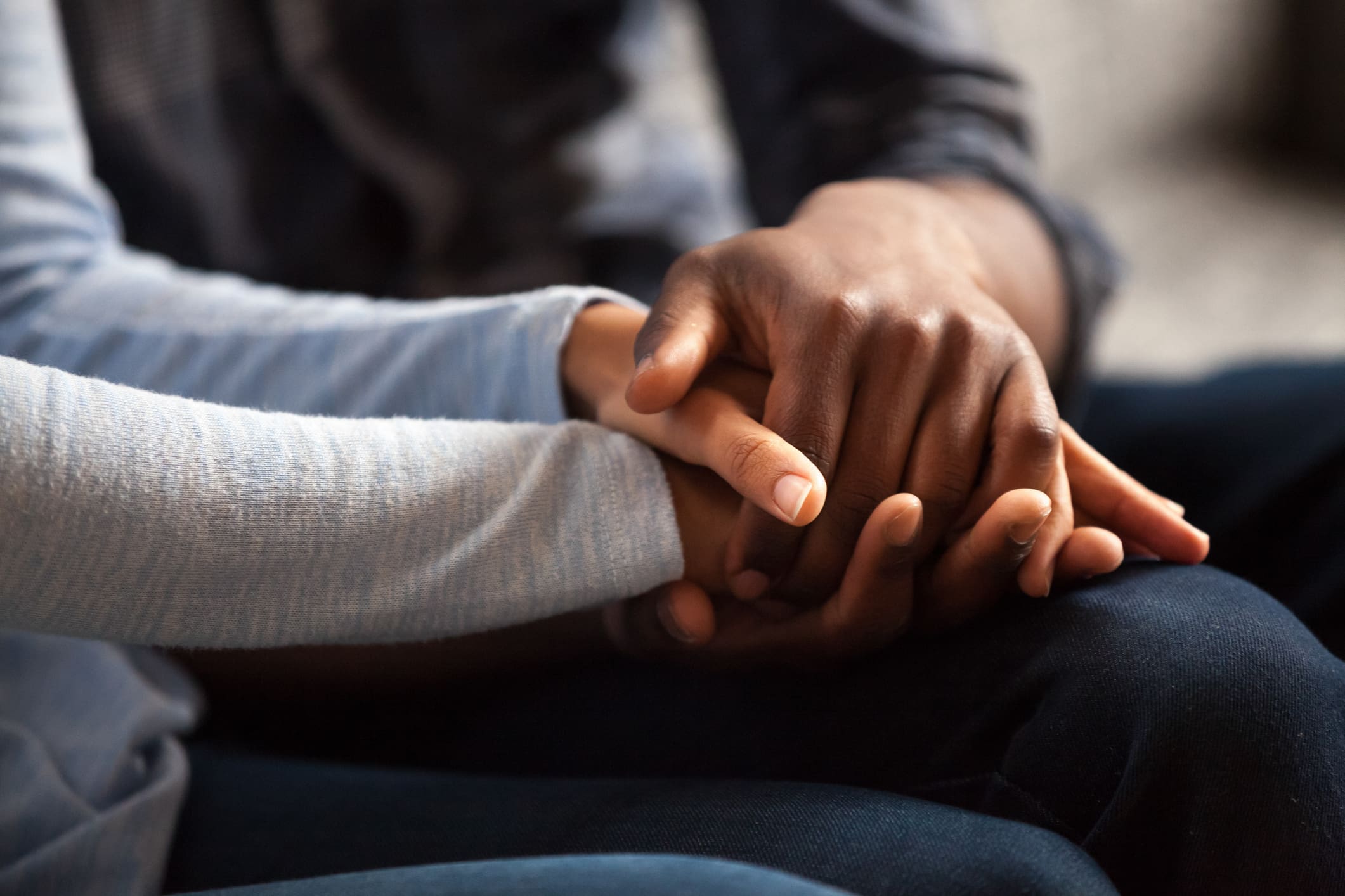 Close-up of two people holding hands, one with darker skin tone