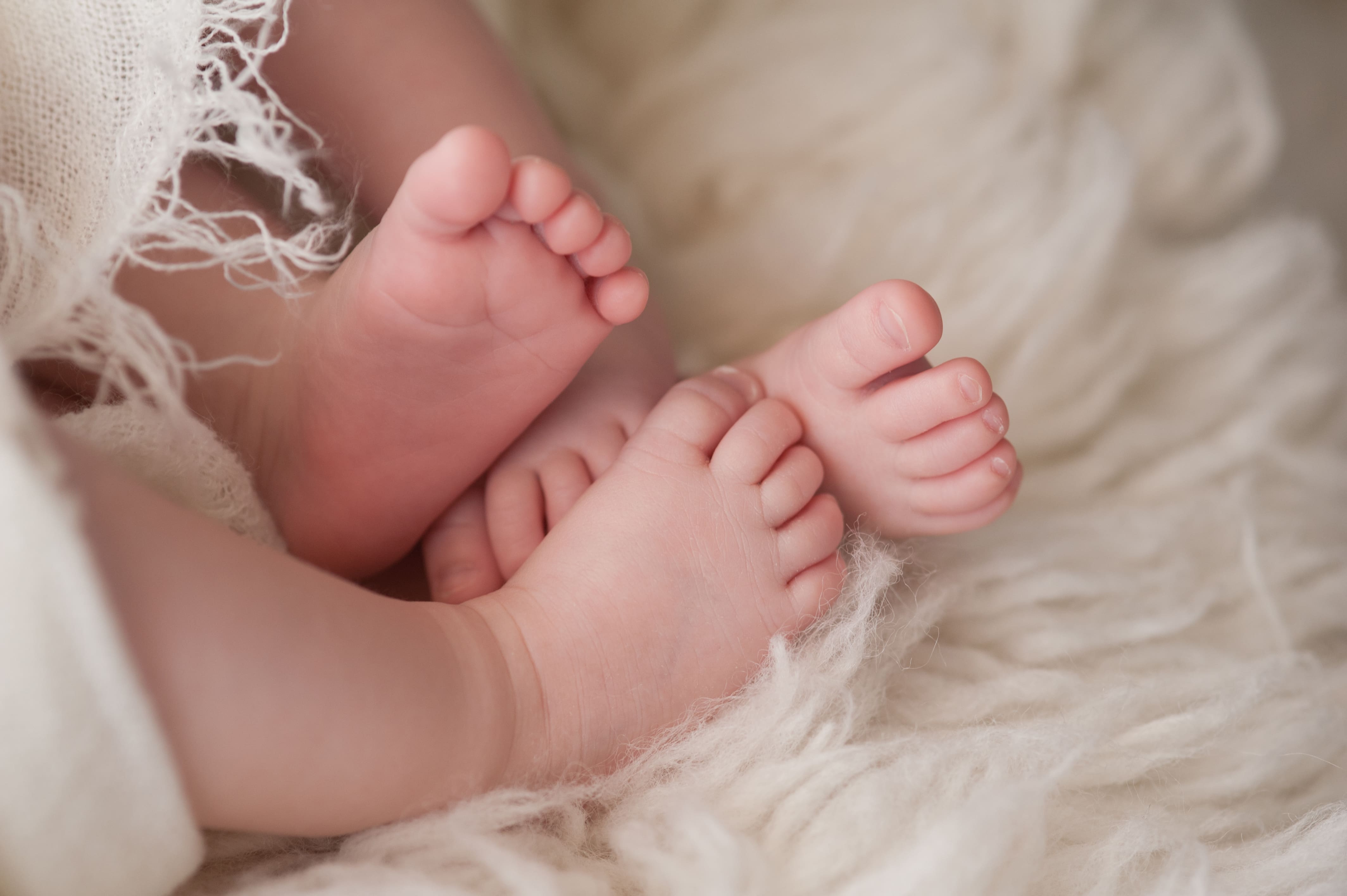 Close-up of the feet of twin baby girls swaddled in blankets