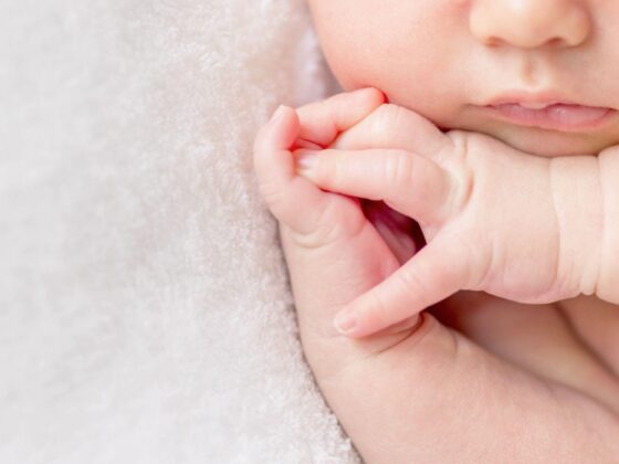 Baby holding adult finger close-up