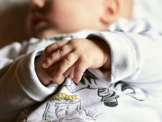 Baby lying down with hands clasped