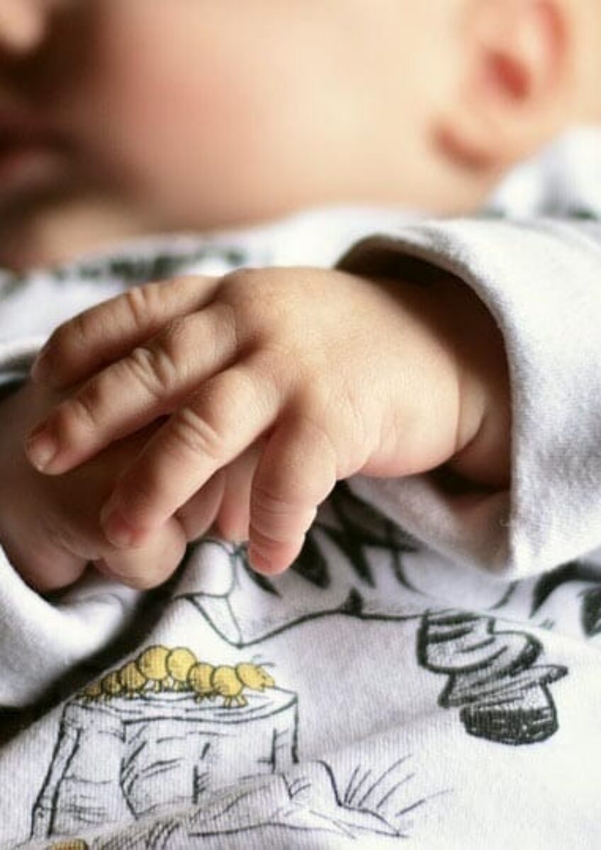 Baby lying down with hands clasped