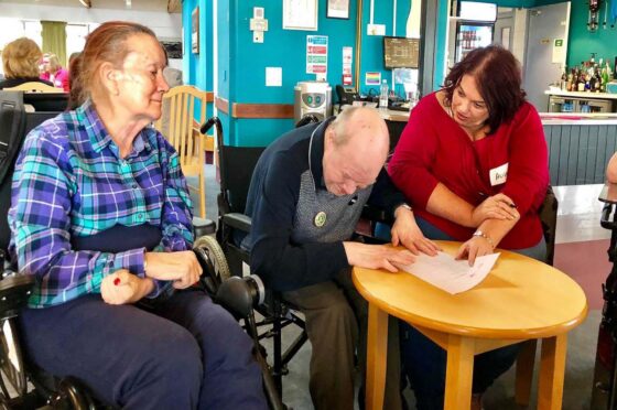 Care home staff helping residents at table