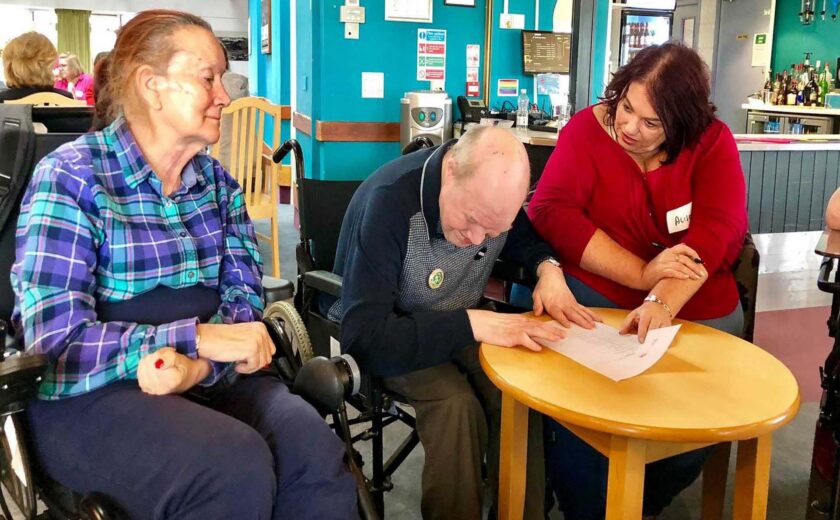 Care home staff helping residents at table