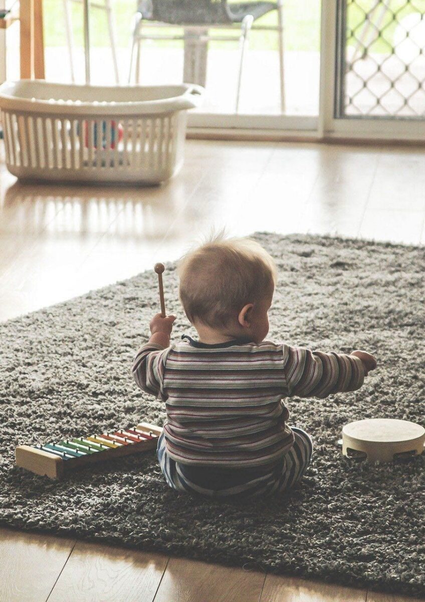 Child sitting on rug with toy piano