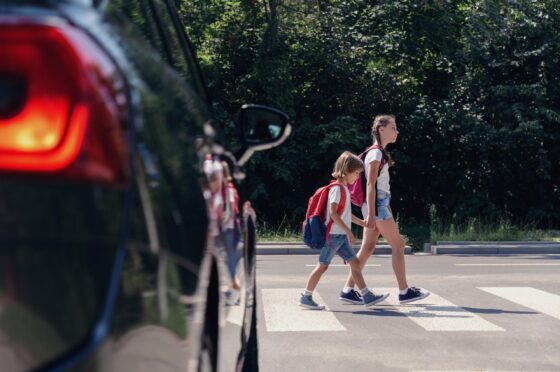 Children crossing road near parked car