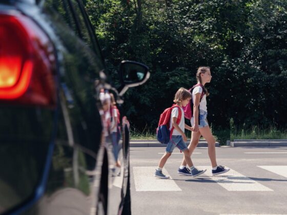 Children crossing road near parked car