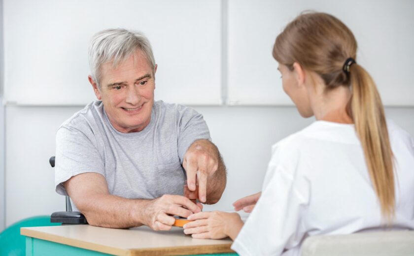Clinician supporting man during hand therapy