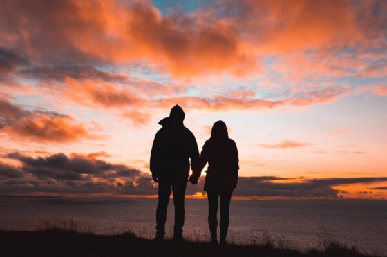 Couple silhouette holding hands at sunset