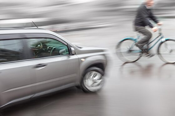 Cyclist riding beside passing car