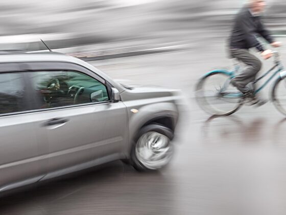 Cyclist riding beside passing car