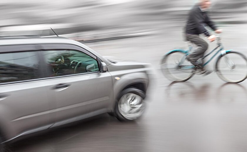 Cyclist riding beside passing car