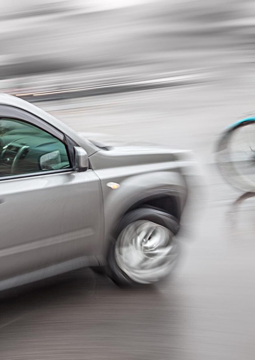 Cyclist riding beside passing car