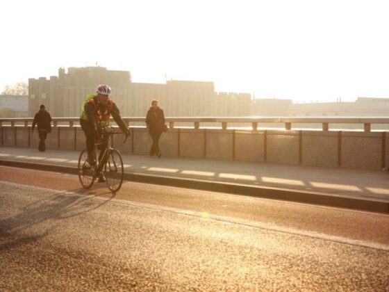 Cyclist riding over bridge at sunset