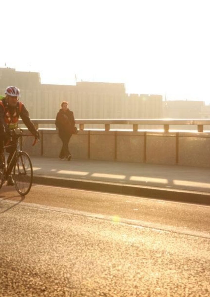 Cyclist riding over bridge at sunset
