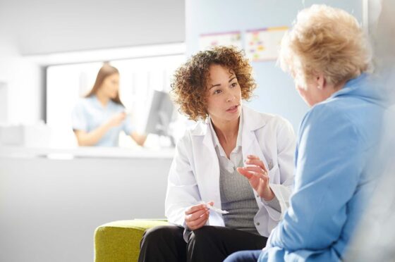 Doctor advising older patient in clinic waiting area