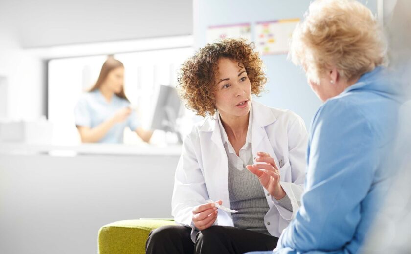 Doctor advising older patient in clinic waiting area