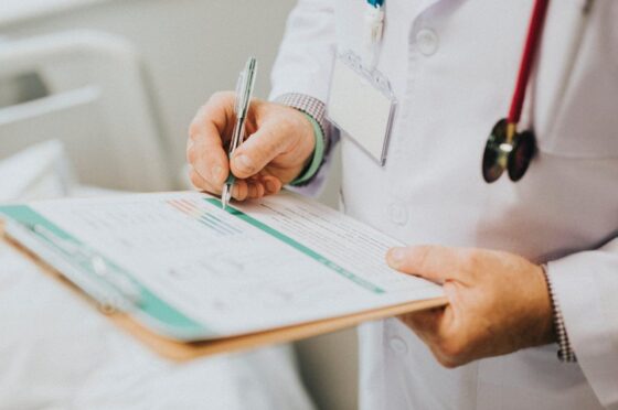 Doctor completing patient notes on clipboard