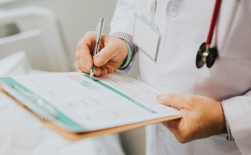Doctor completing patient notes on clipboard