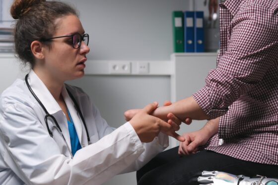 Doctor examining patient's hand in consultation