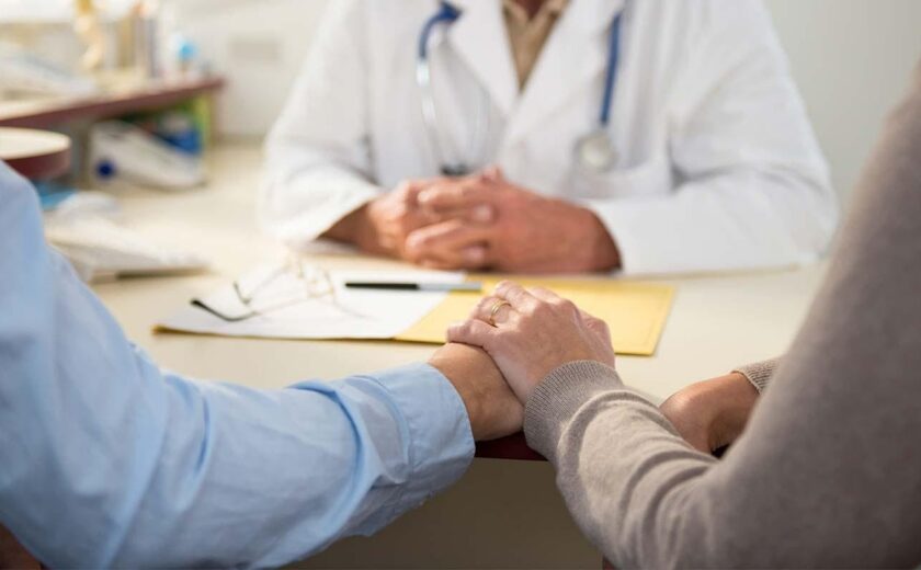 Doctor holding patient's hand during consultation