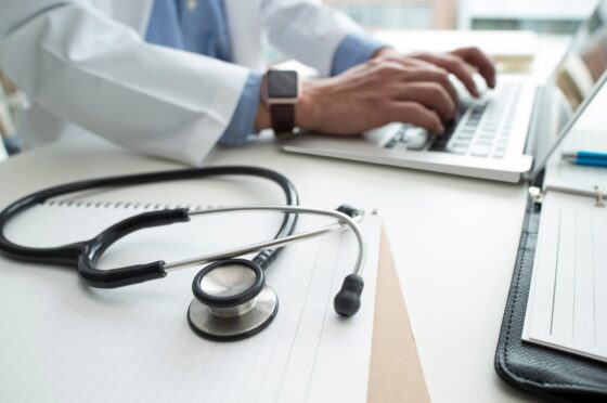 Doctor typing at desk with stethoscope