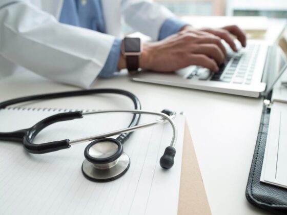 Doctor typing at desk with stethoscope