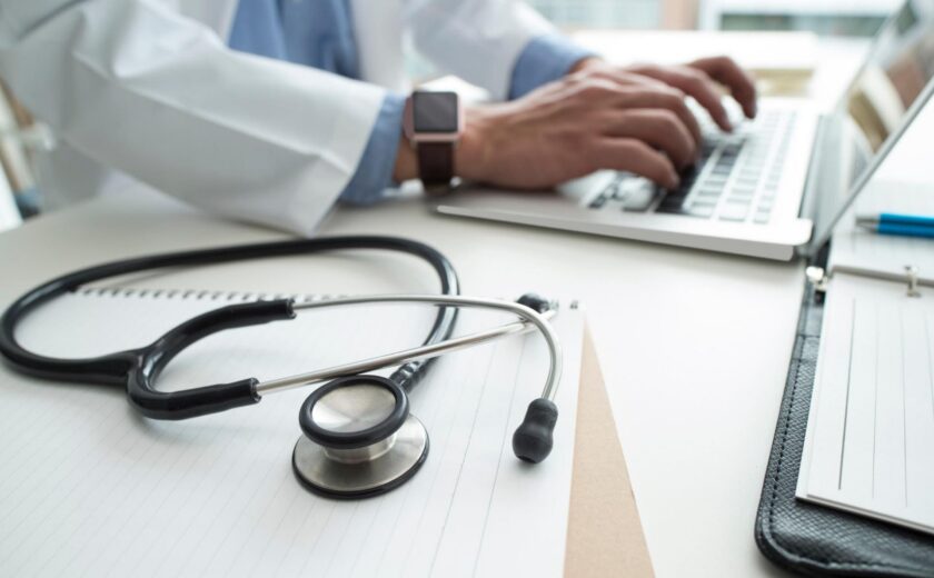 Doctor typing at desk with stethoscope