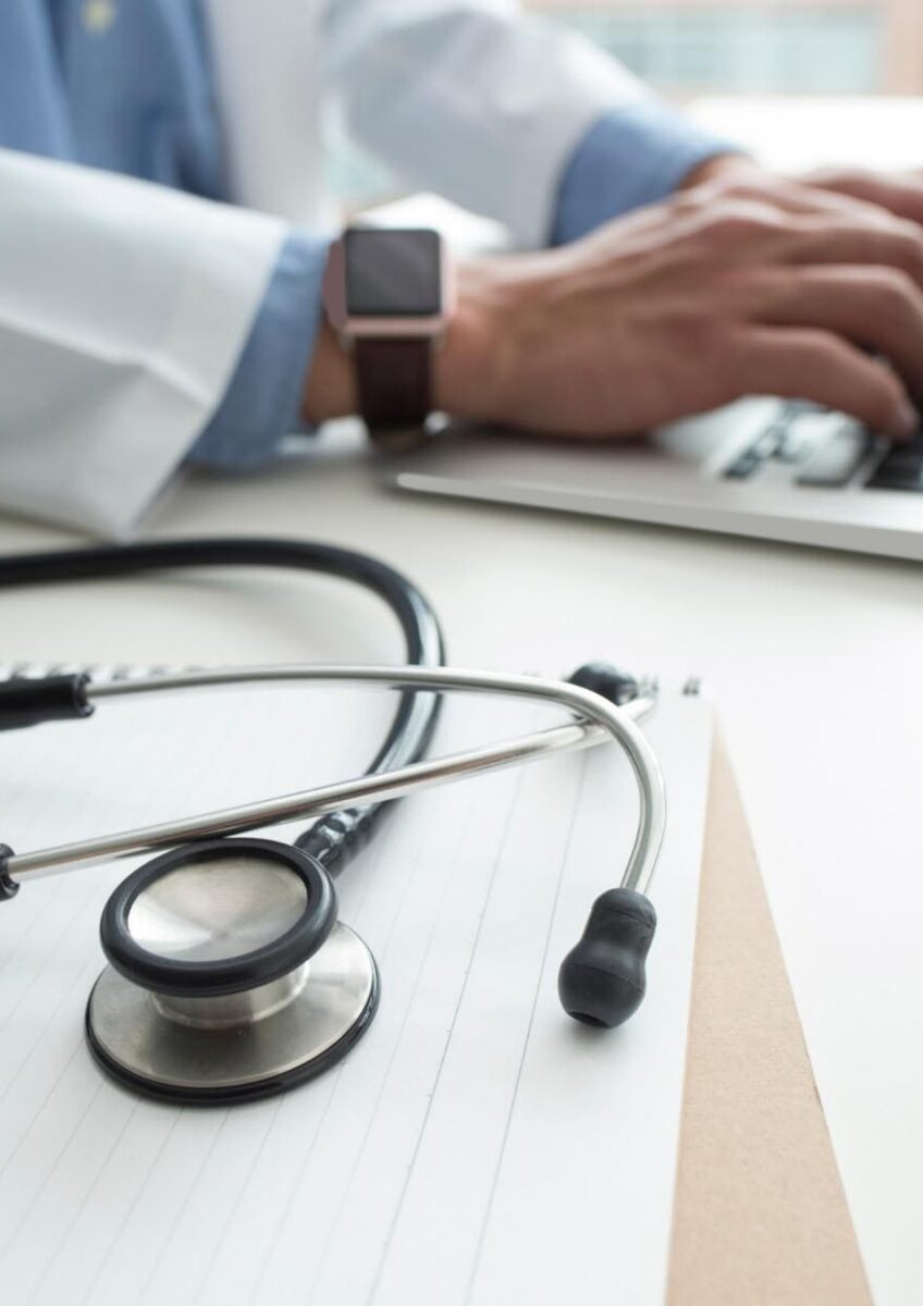 Doctor typing at desk with stethoscope