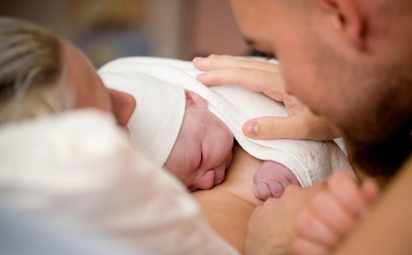 Father resting hand on newborn baby